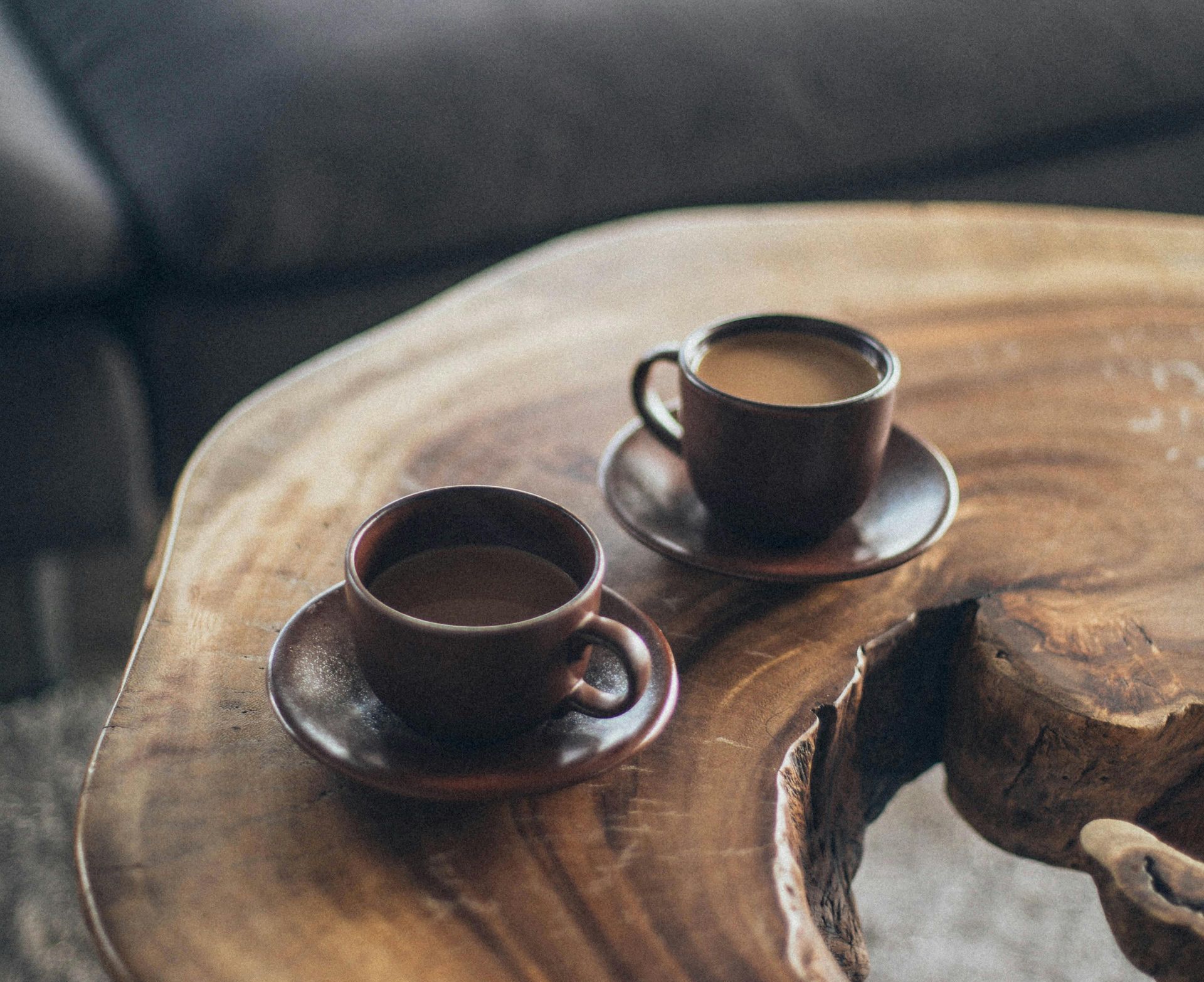 Two cups of coffee are sitting on a wooden table.
