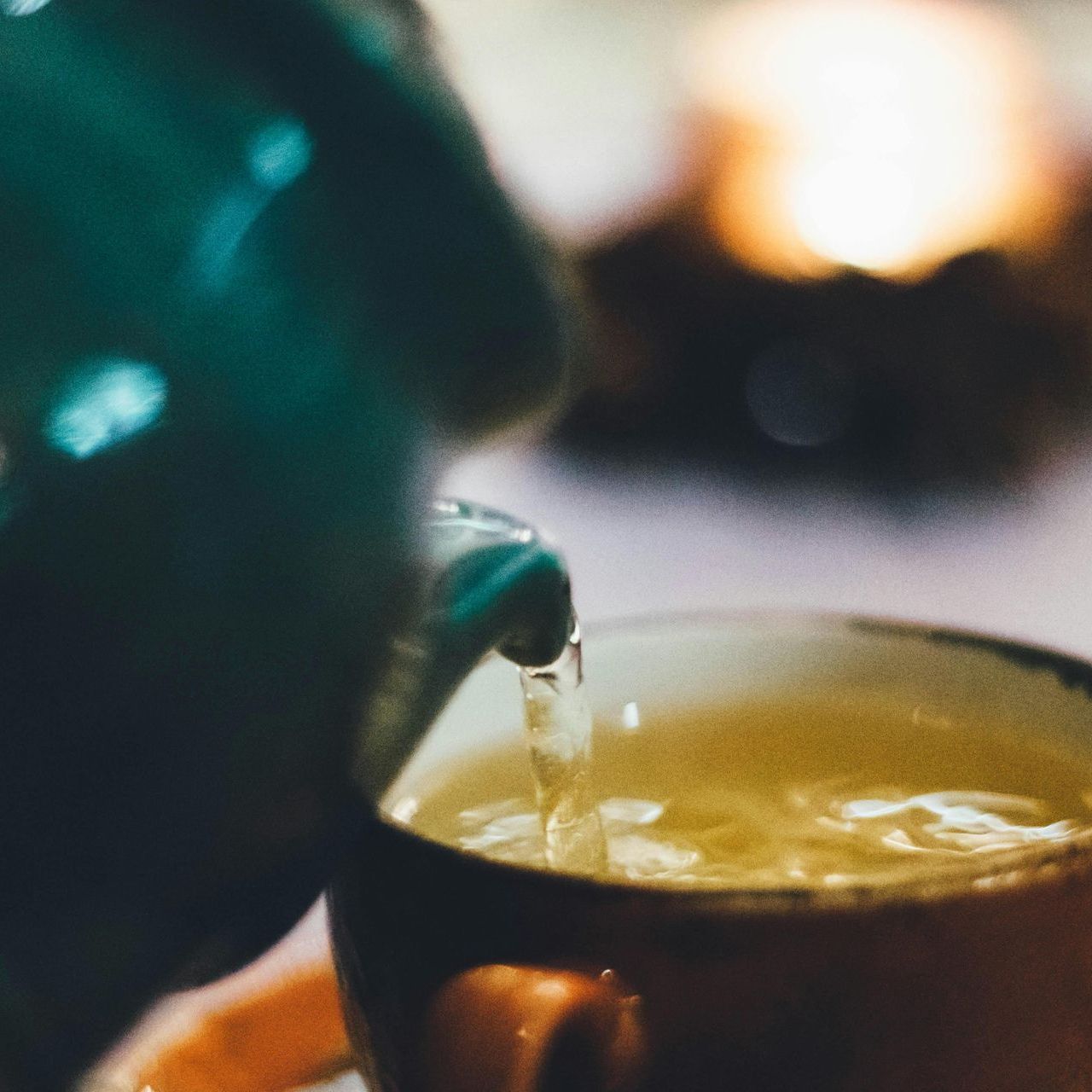 A cup of tea is being poured from a teapot into a cup.