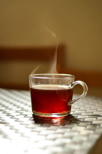 A cup of red tea with steam coming out of it