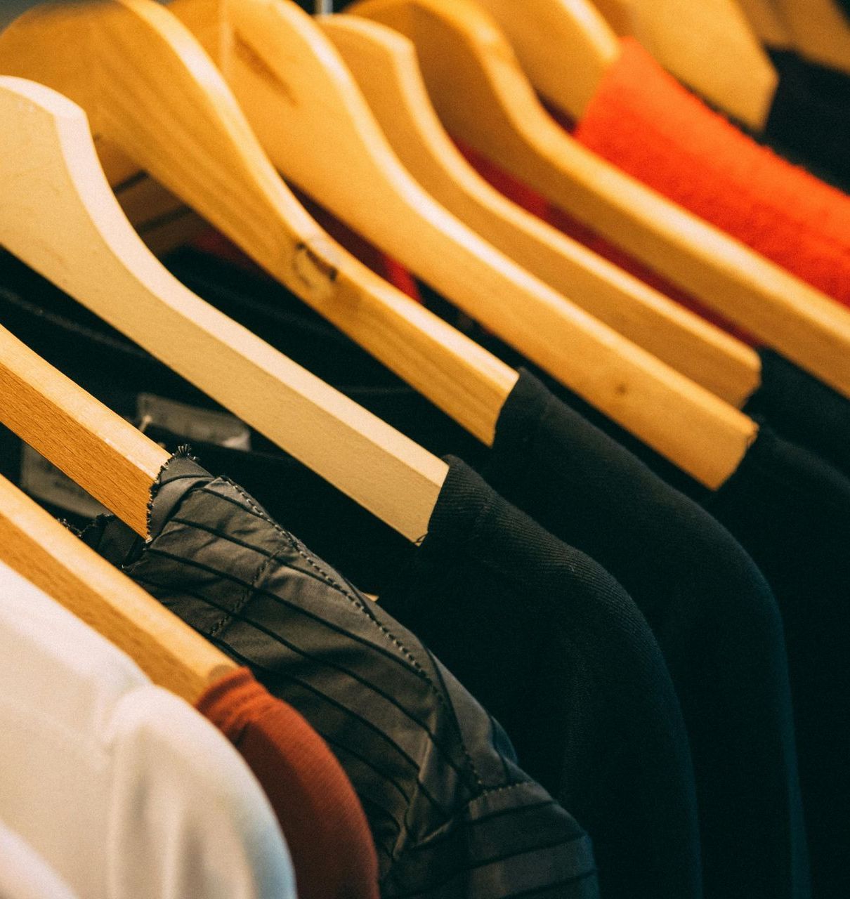 A bunch of clothes are hanging on wooden hangers