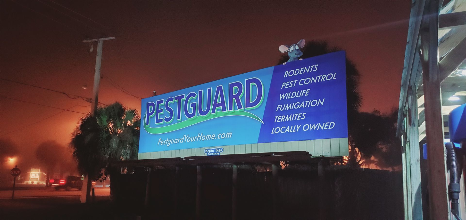 A Stu-Art billboard for pestguard is lit up at night