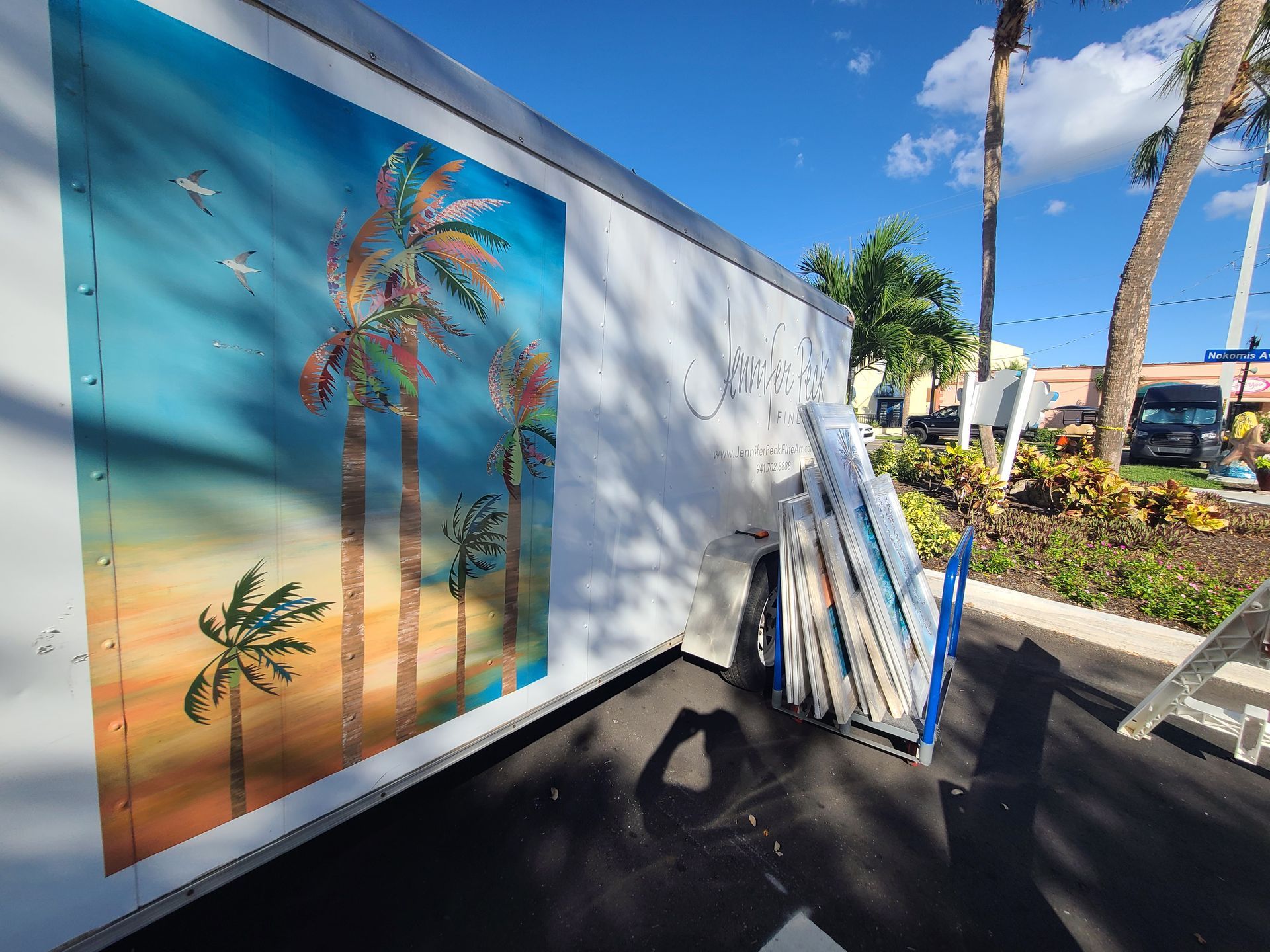 A white trailer with a painting of palm trees on it