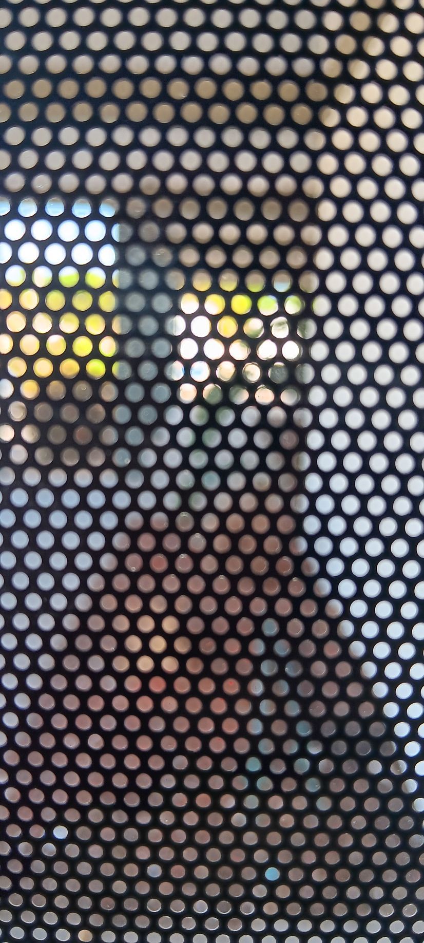 A close up of a metal fence with holes in it.