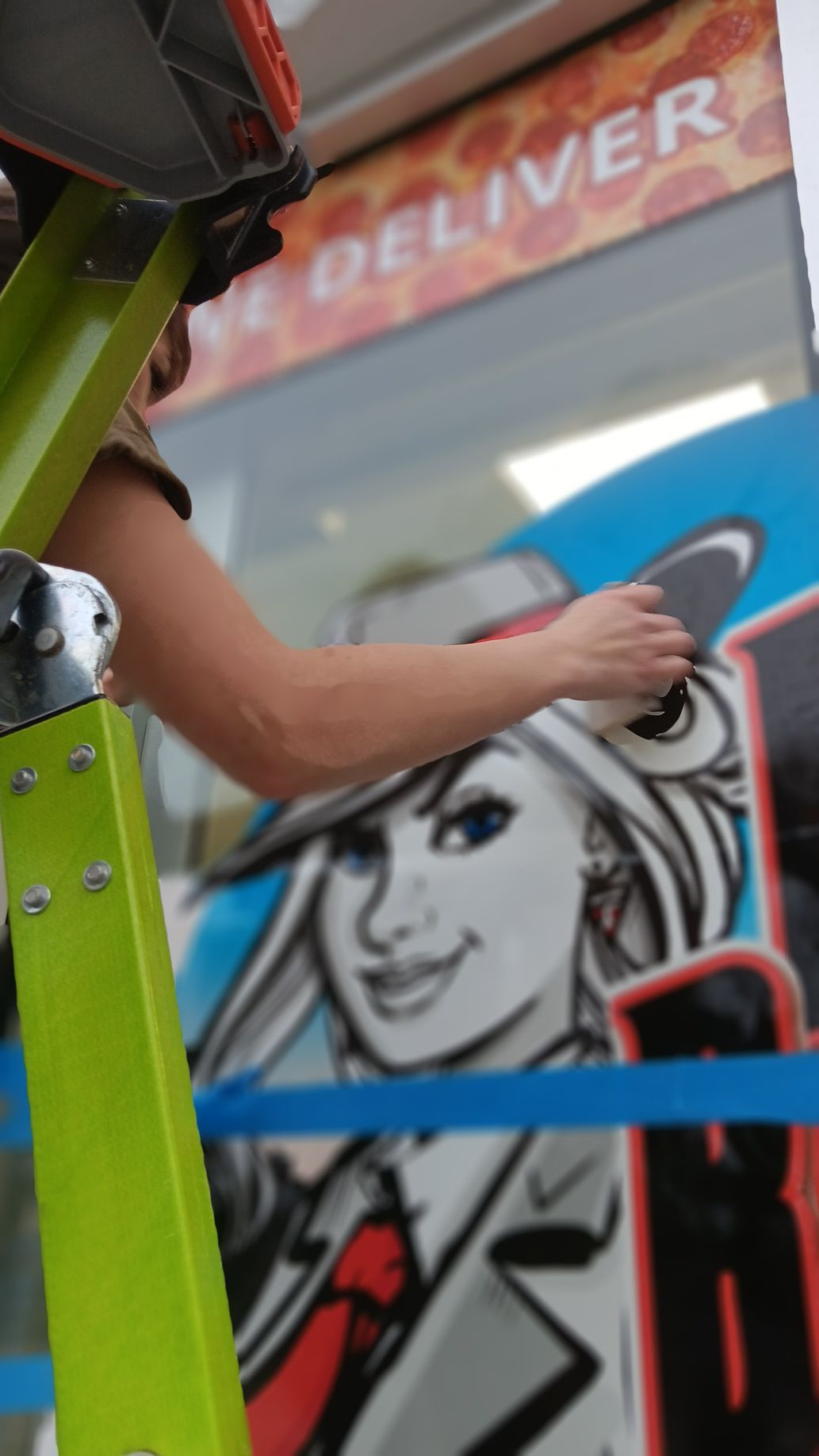A woman is standing on a ladder painting a picture of a woman