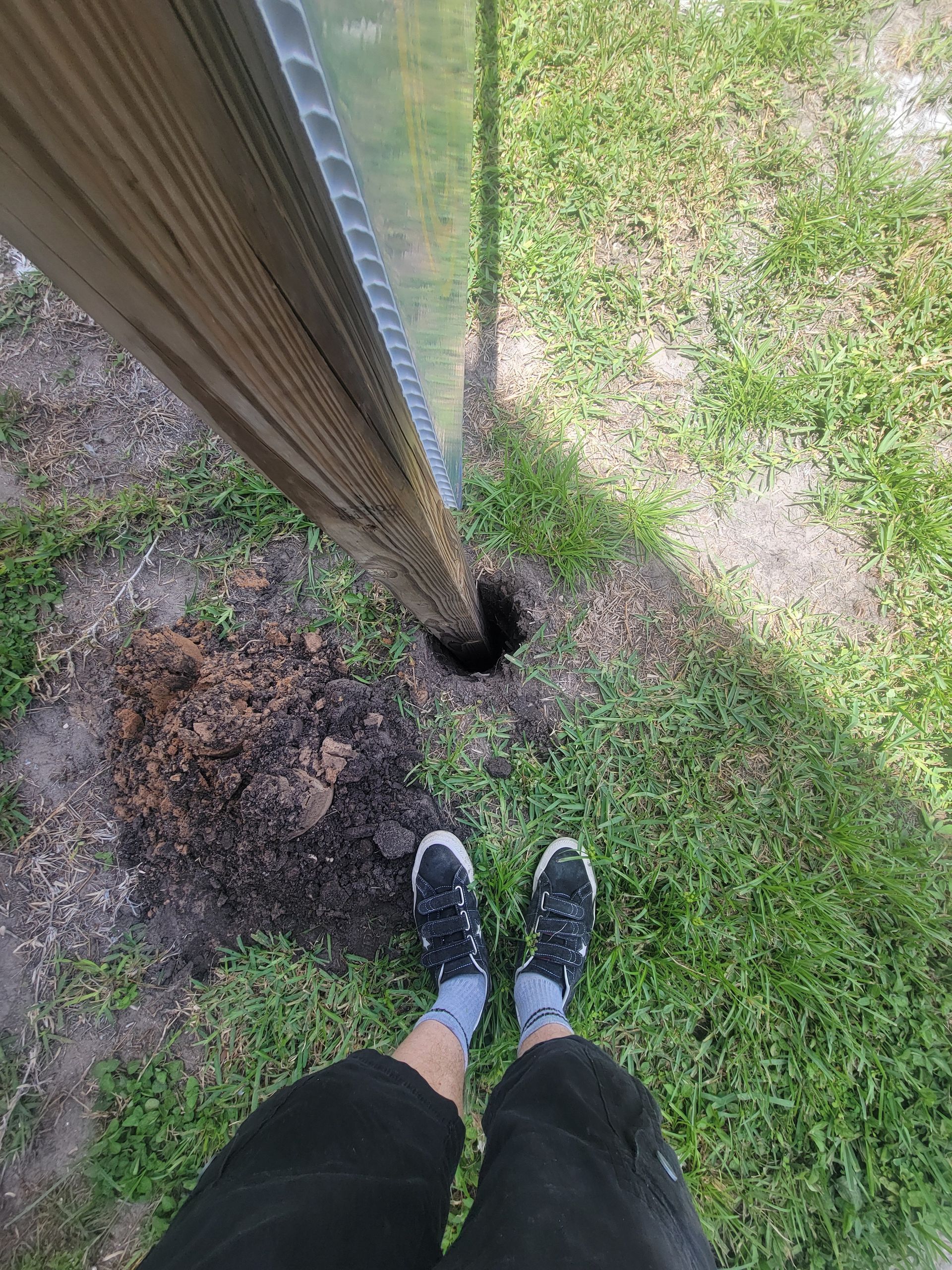 A person is standing in the grass next to a fence.