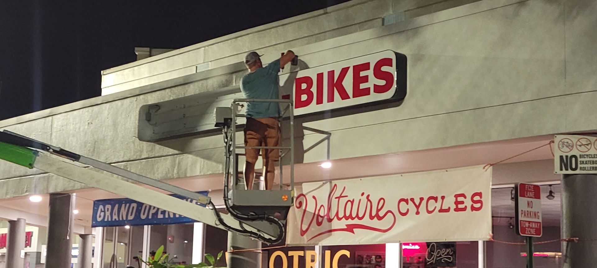 A man on a crane is cleaning the bikes sign