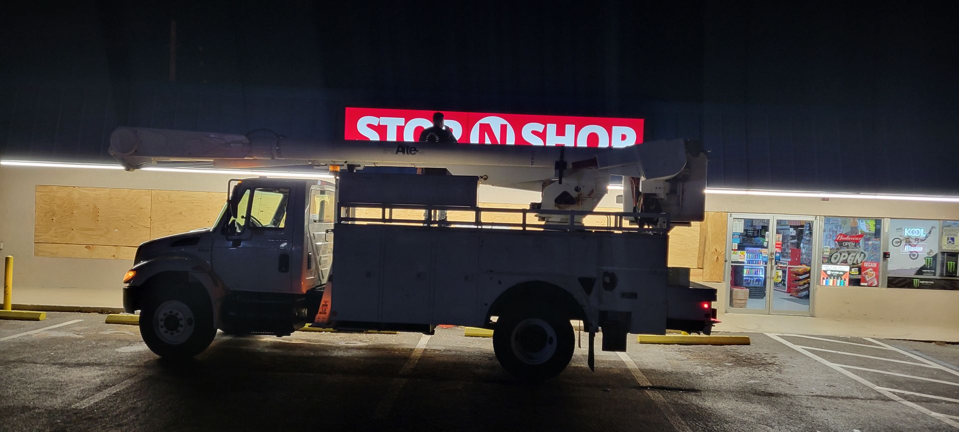 A utility truck is parked in front of a store at night.
