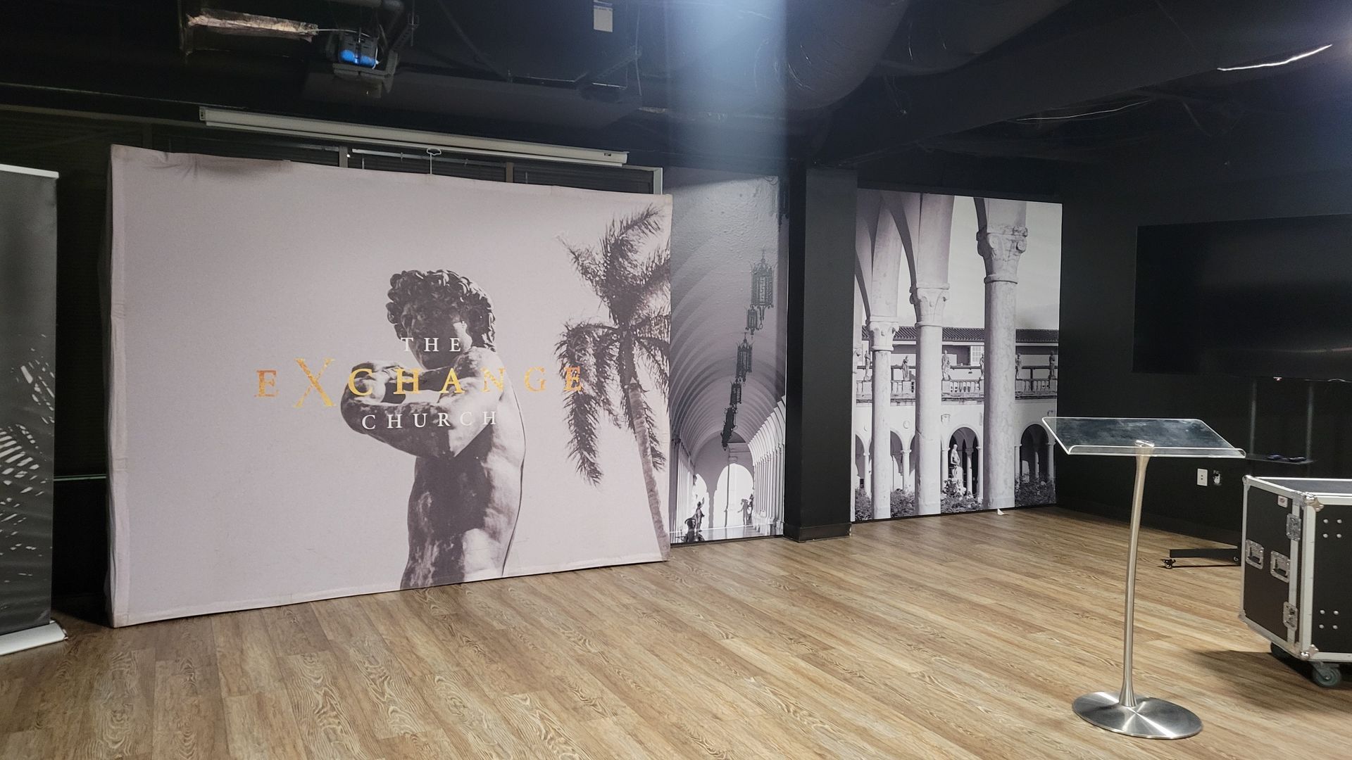 A large room with a wooden floor and a painting on the wall.