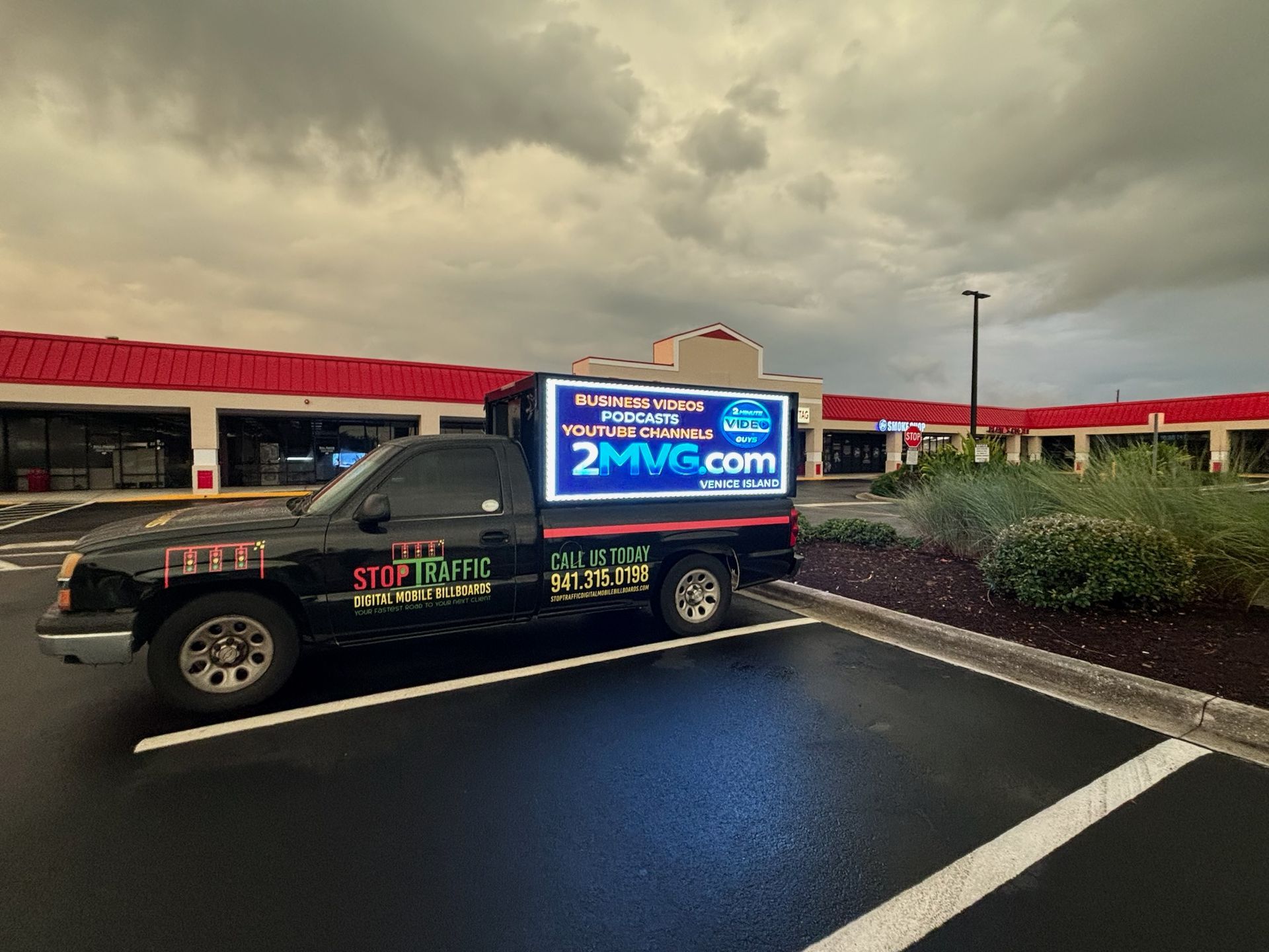 A truck with a sign on the back of it is parked in a parking lot.