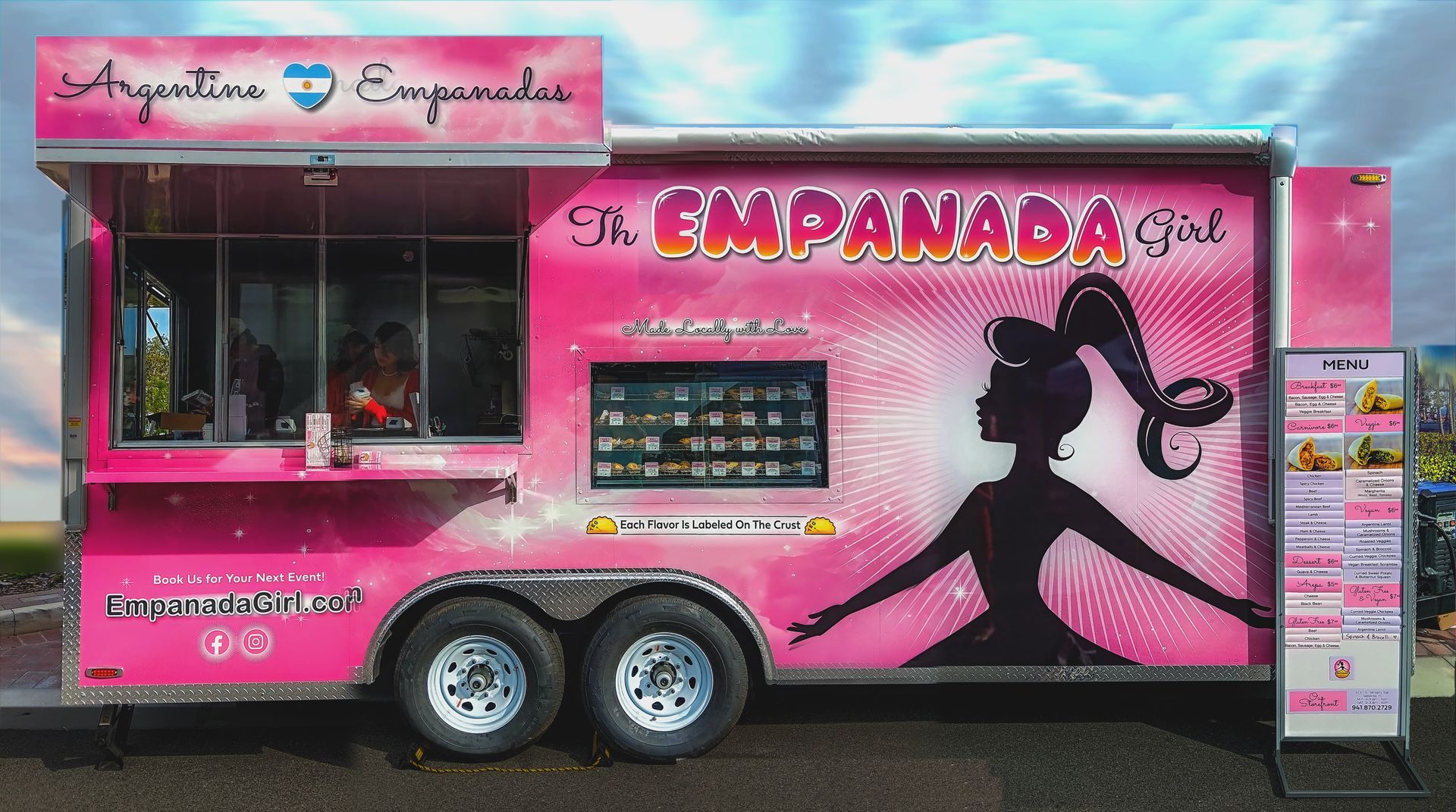 A pink food truck that says the empanada girl on it