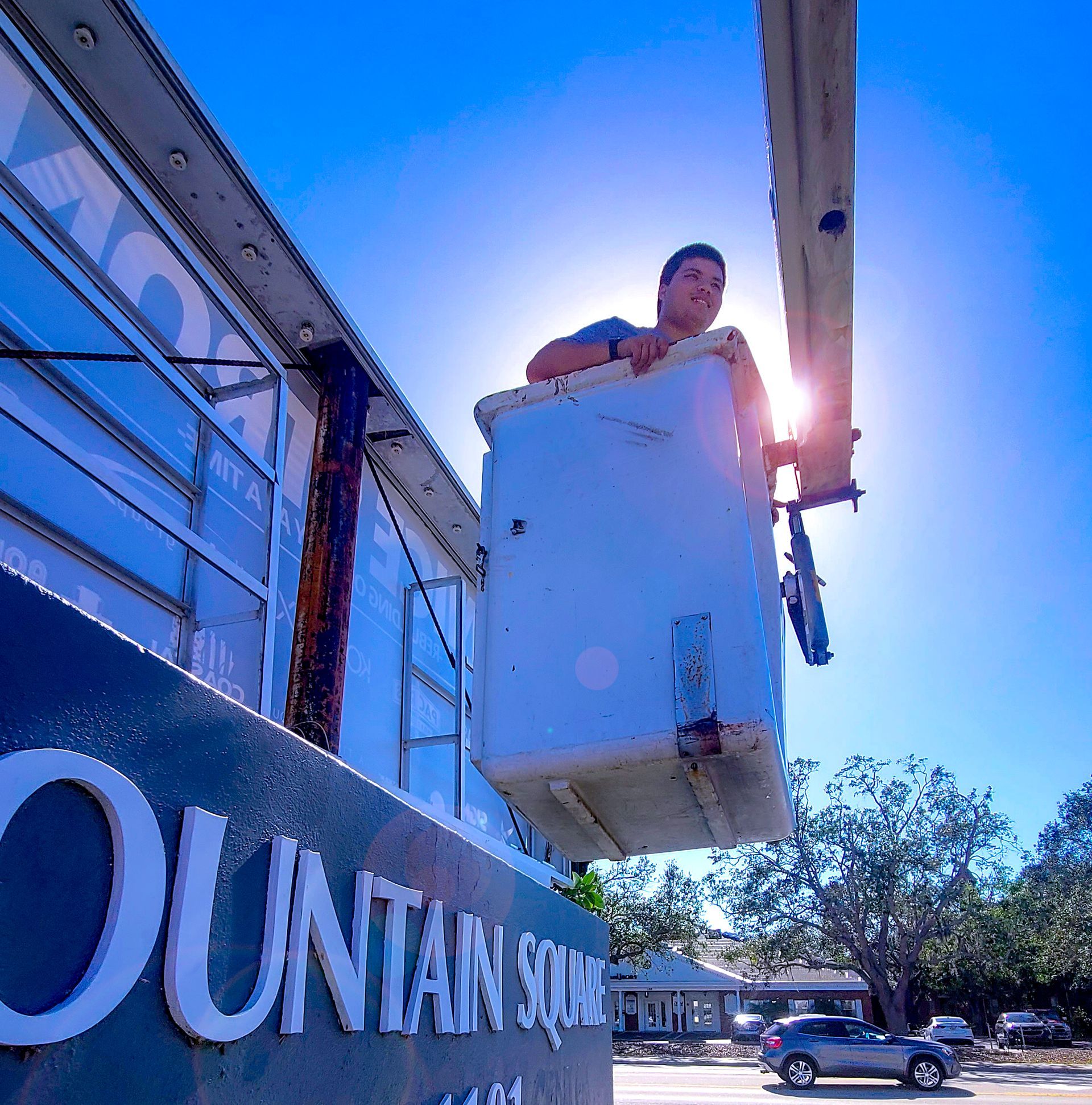 A man in a bucket is working on a sign that says mountain square