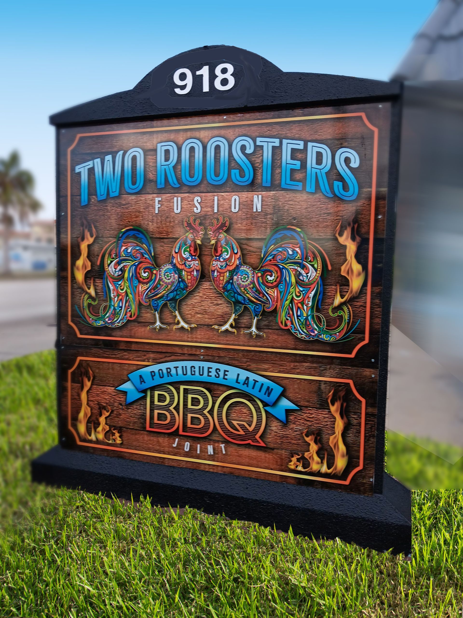 A sign for two roosters bbq is sitting in the grass