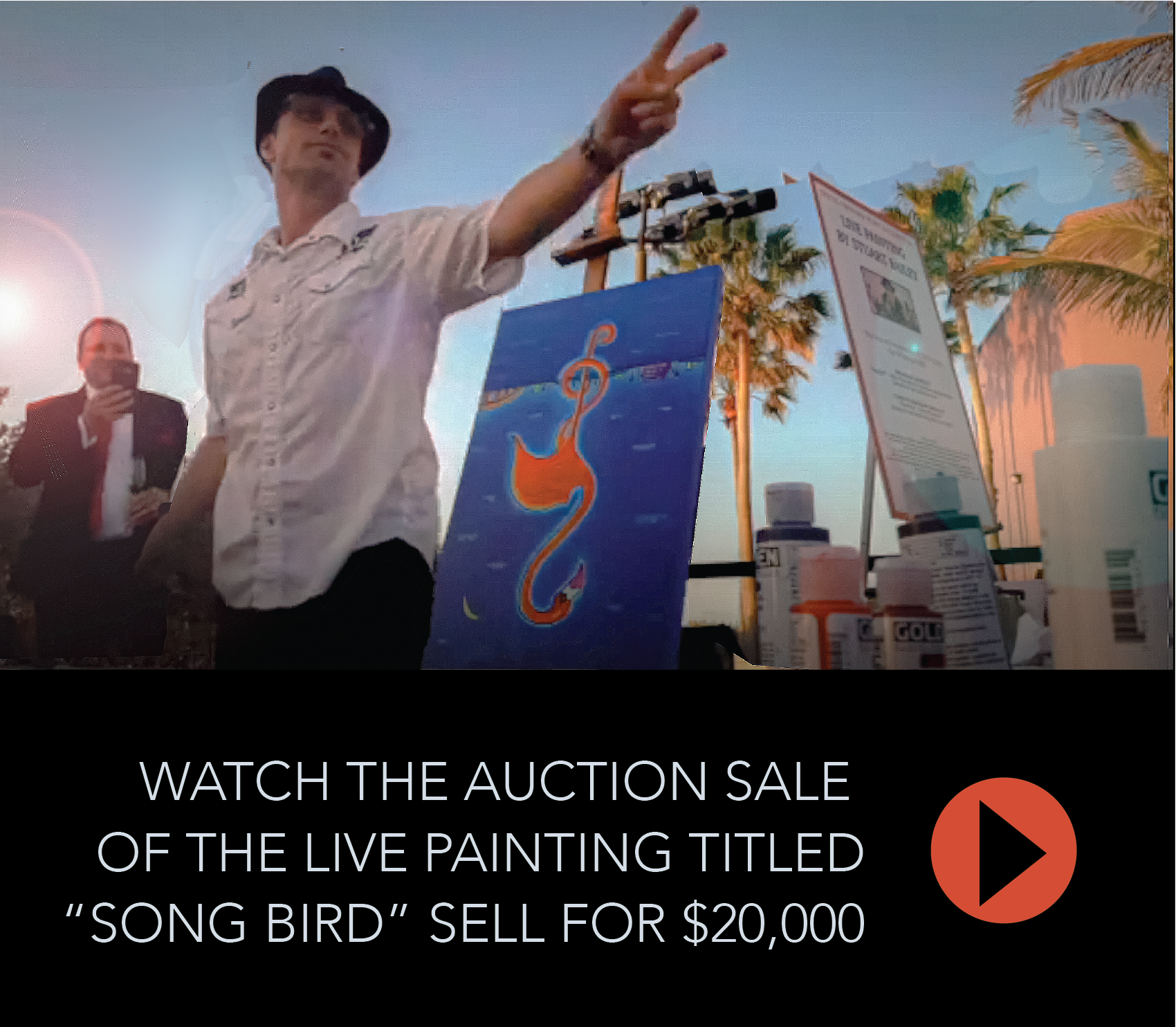 A man standing in front of a painting that says watch the auction sale of the live painting titled 