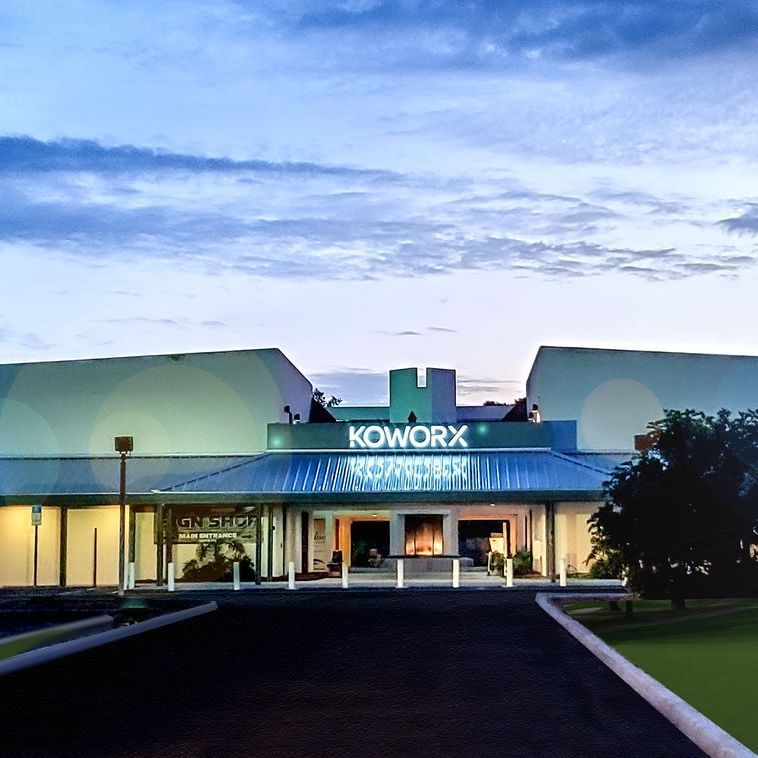 A white building with blue awnings is next to a road