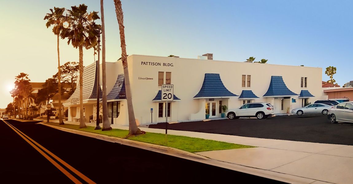 A white building with blue awnings is next to a road