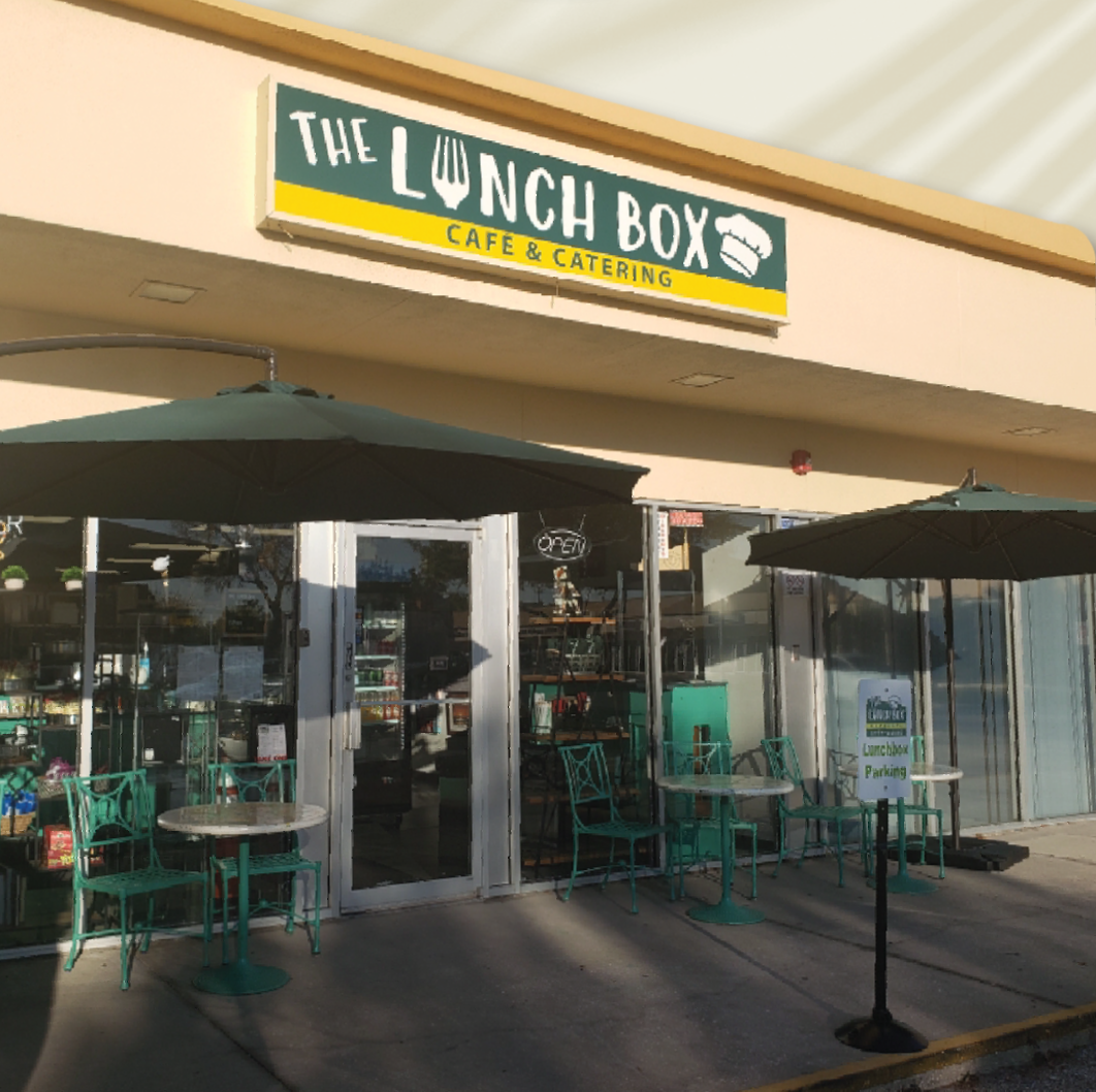 A restaurant called the lunch box has tables and umbrellas outside