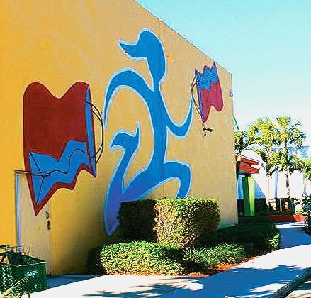 A yellow building with a blue and red painting on it
