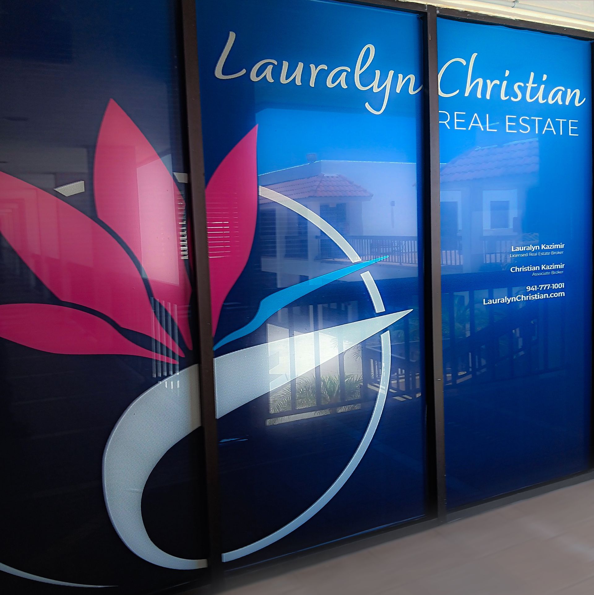 A window sign for Lauralyn Christian real estate with a pink flower on it