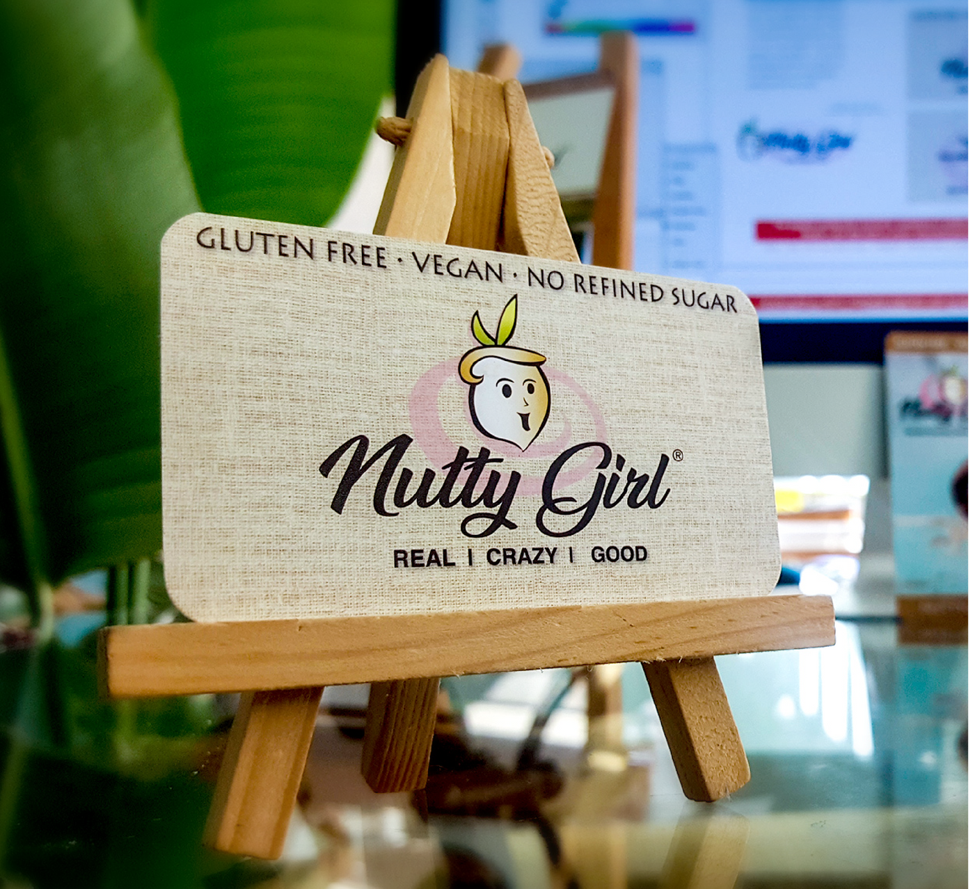 A business card for nutty girl is on a wooden easel