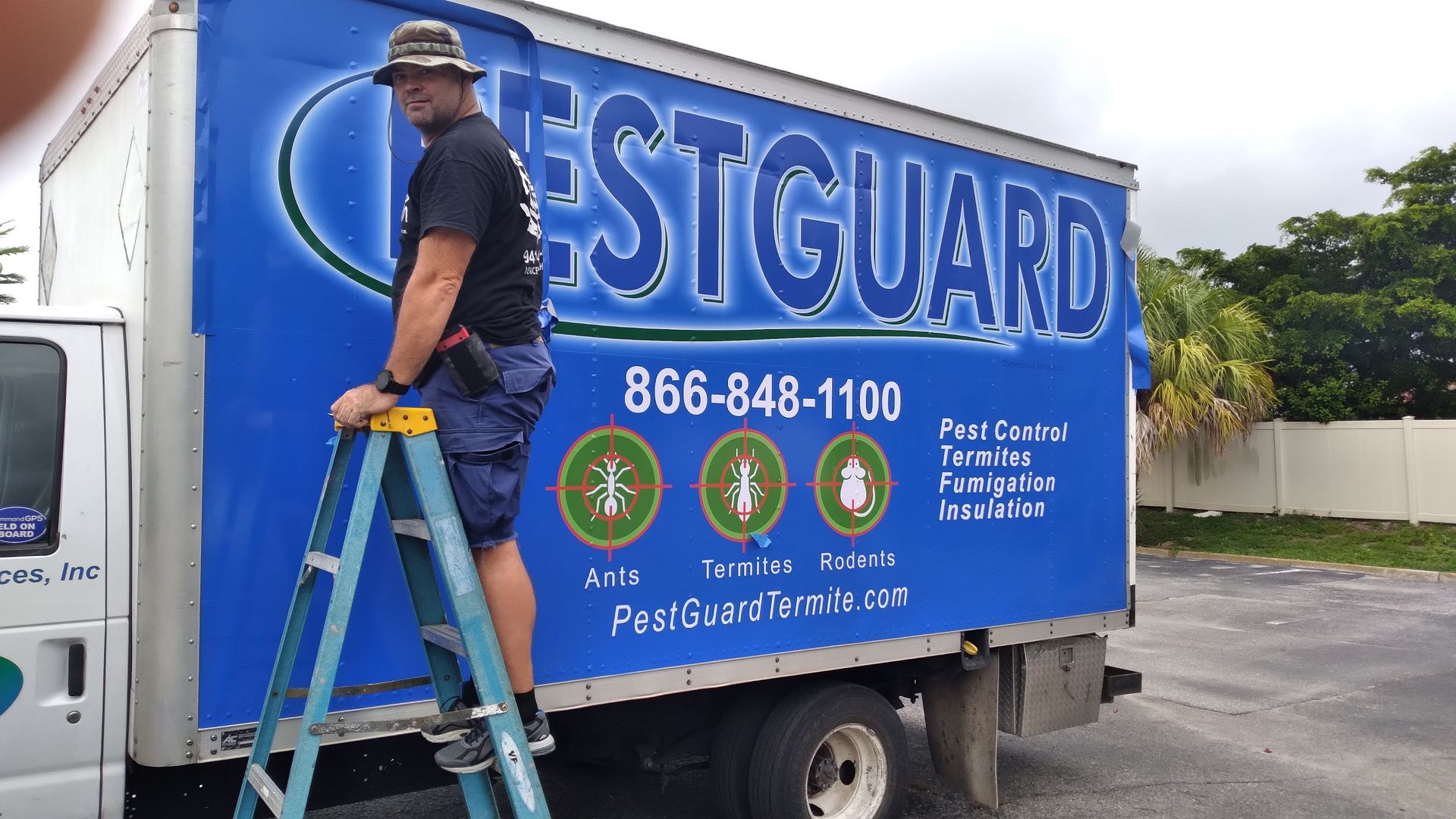 A man standing on a ladder next to a pestguard truck