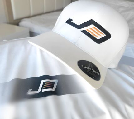 White baseball cap with black and orange logo, on white surface.