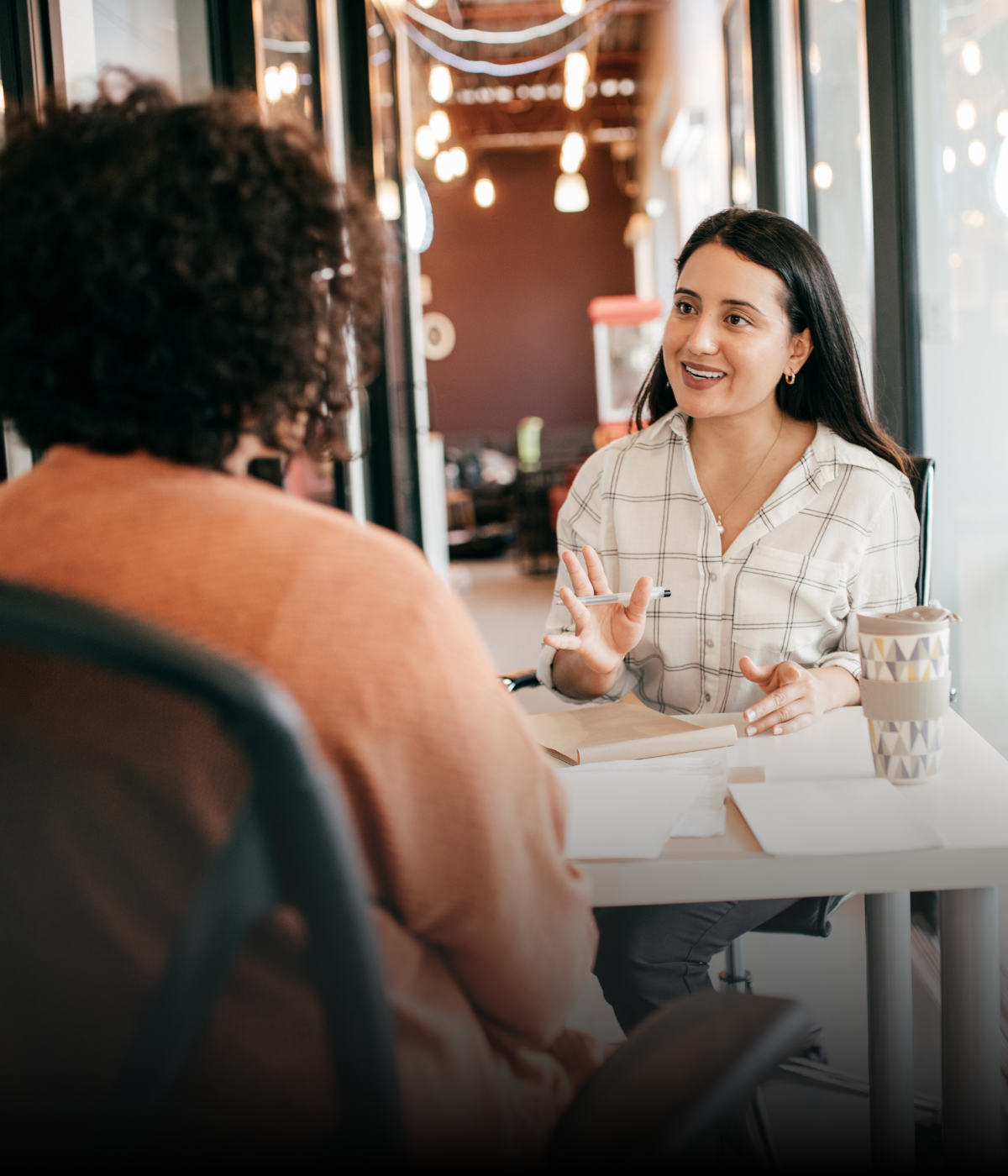 A woman is sitting at a table talking to another woman.