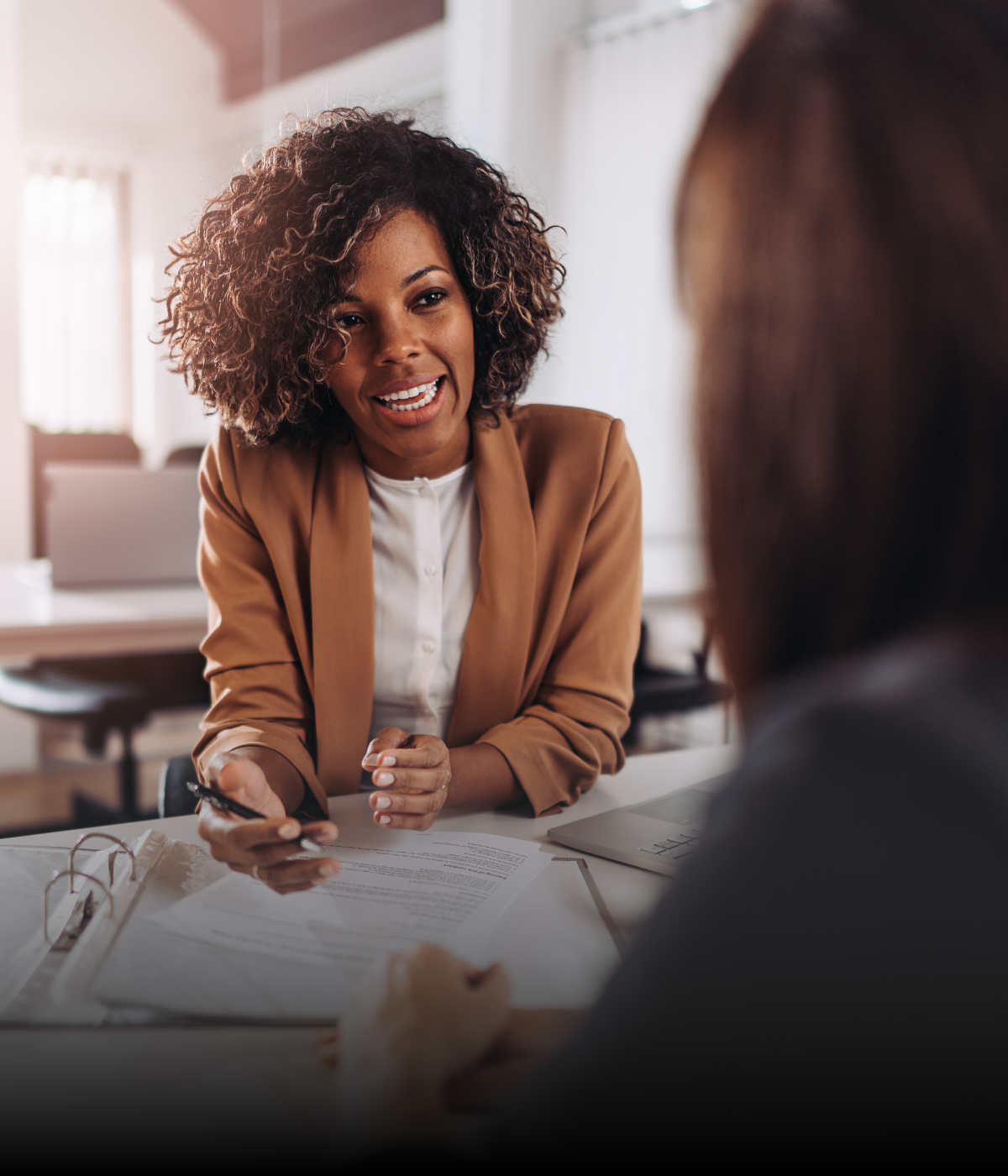 A woman is sitting at a table talking to another woman.