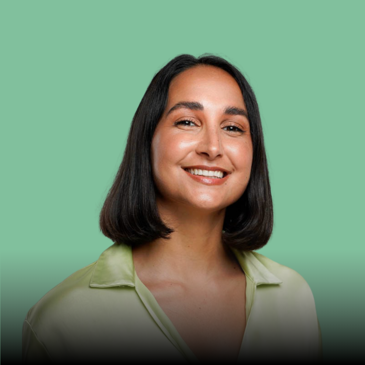 A woman is smiling for the camera while wearing a green shirt.