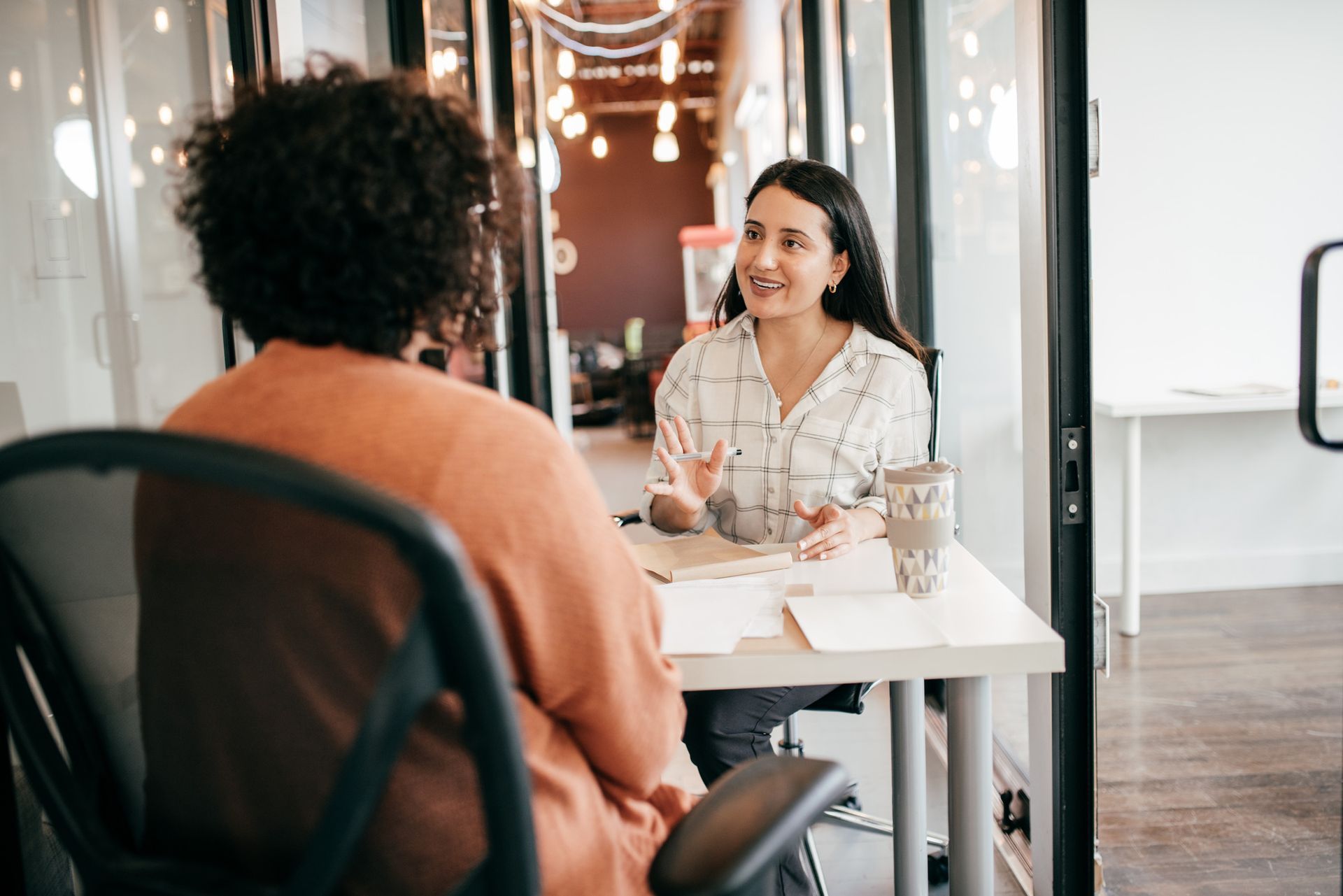 A woman is sitting at a table talking to another woman.