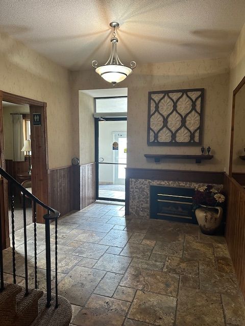 Hallway with stone floor, stairs, door, fireplace, and decorative wall panel.