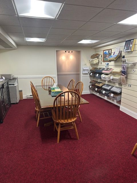 A room with a red carpet, a table and chairs, and items displayed on shelves.