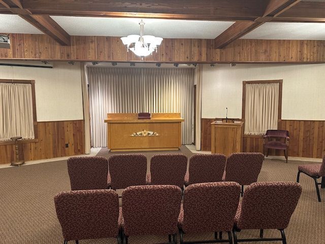 Interior of a funeral home: beige walls, wooden accents, chairs facing a casket.