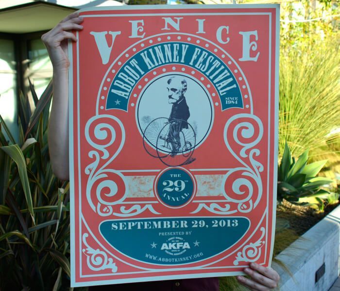 A person is holding a poster for the venice abbot kinney festival