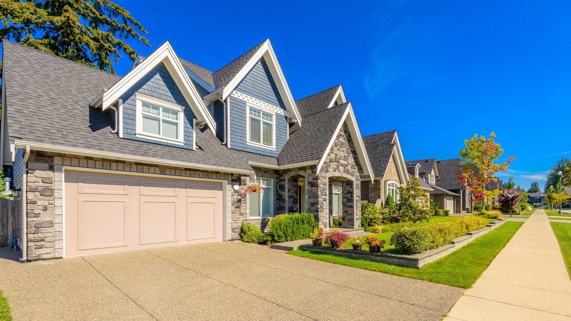 A large house with two garages and a lush green lawn.