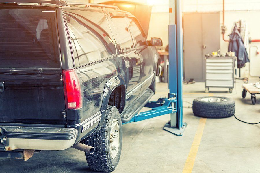 A black suv is sitting on a lift in a garage.