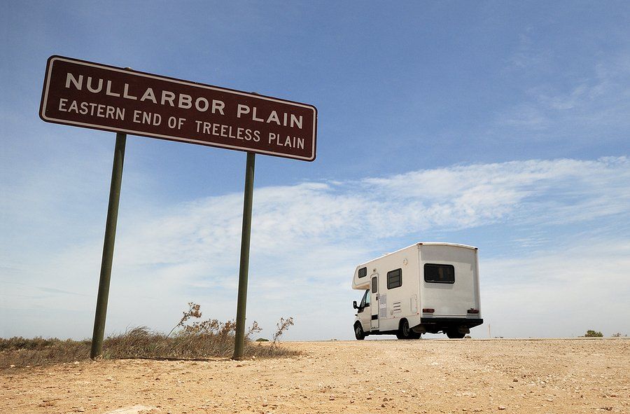 A white van is parked in front of a sign that says nullarbor plain