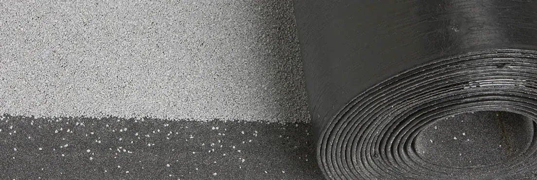 A black and white photo of a roll of carpet next to a wall.