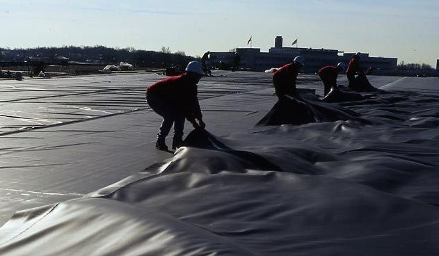 A group of people are working on a large piece of plastic
