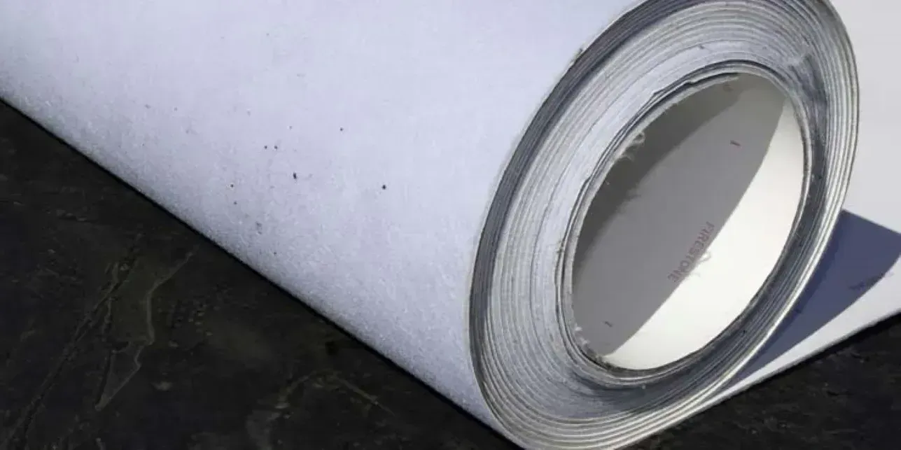 A roll of white tape is sitting on a black surface.