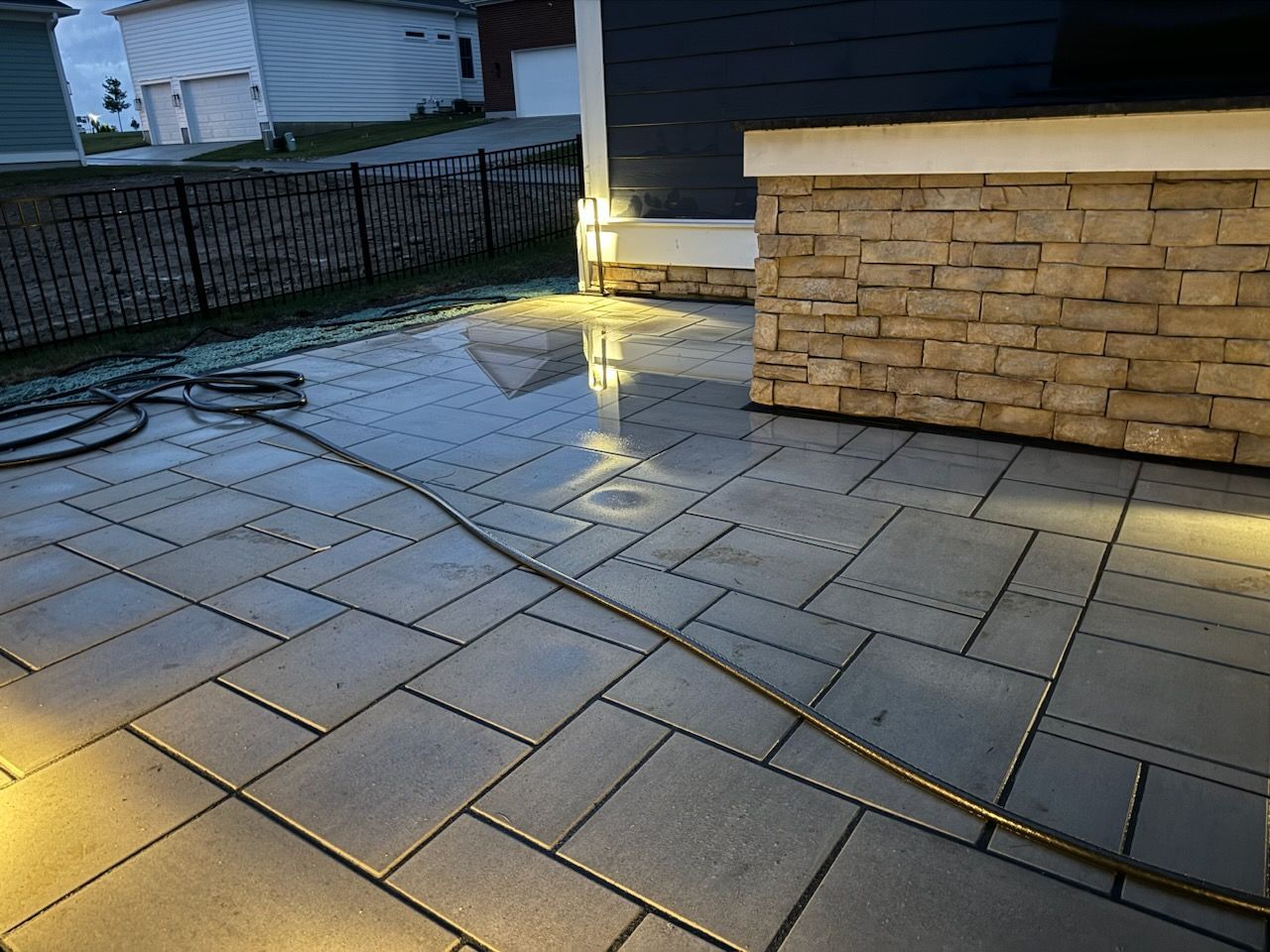 A hose is connected to a brick wall on a patio