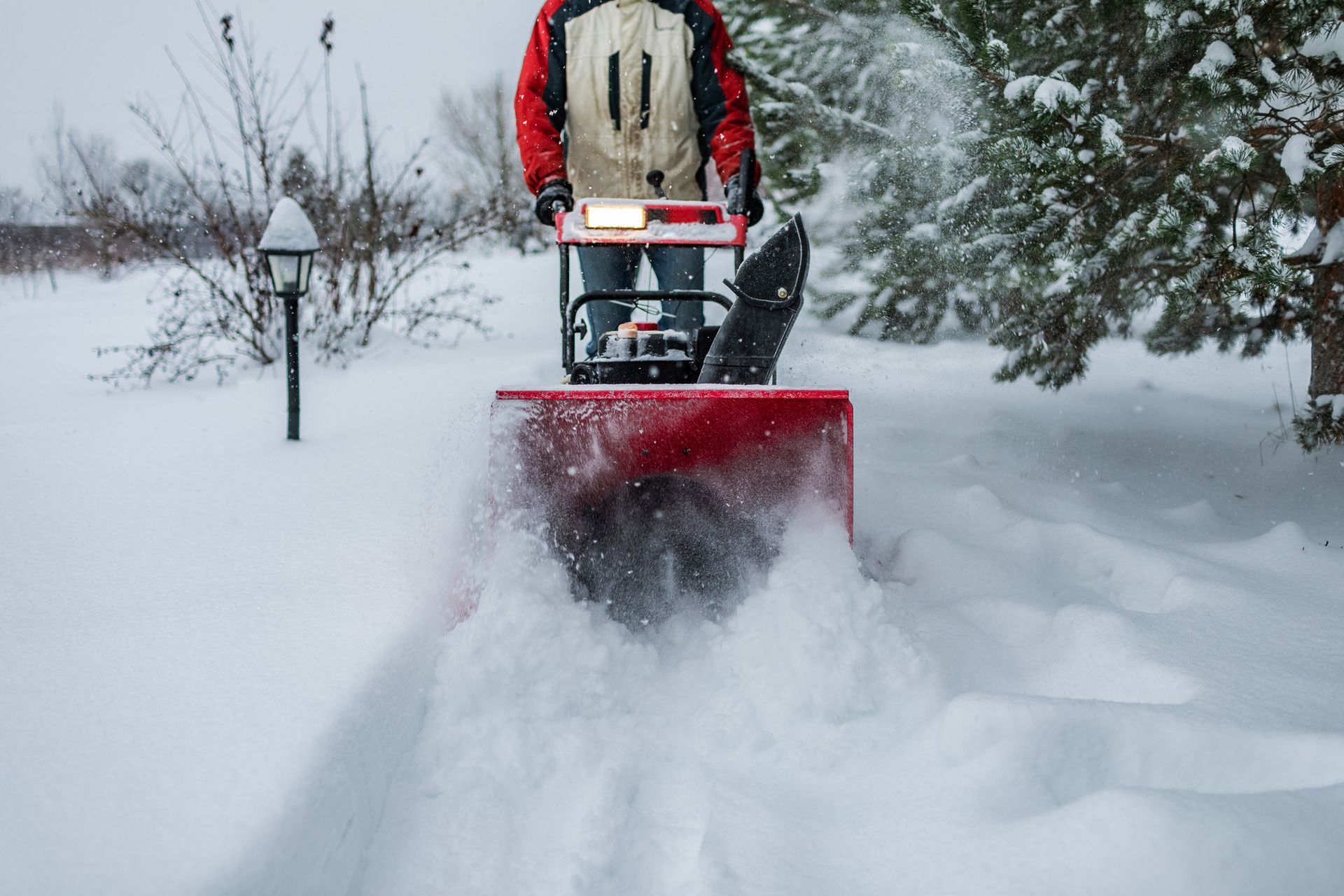 A man is using a snow blower to clear snow from a driveway.