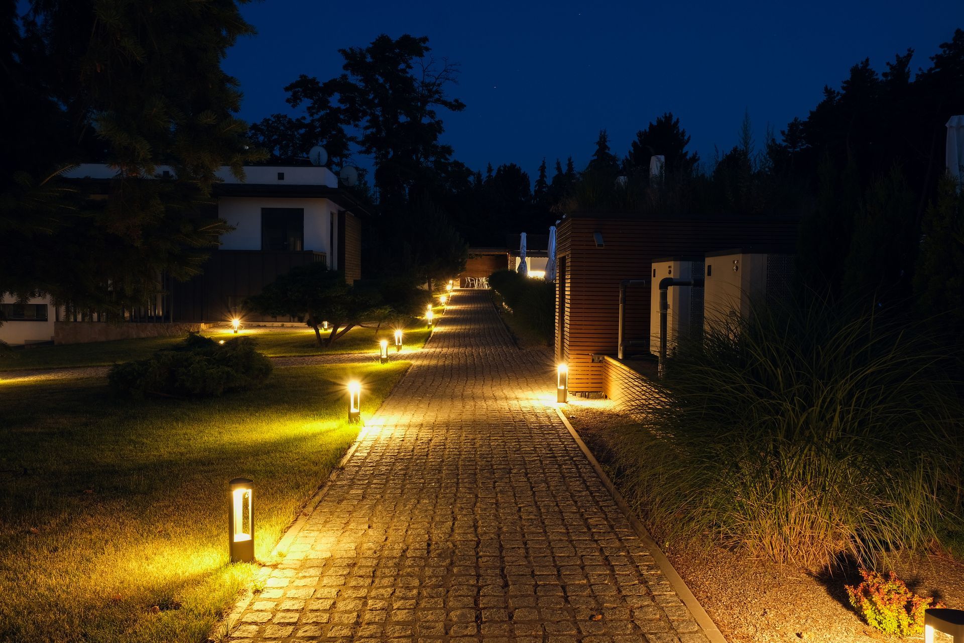 A brick walkway is lit up at night.