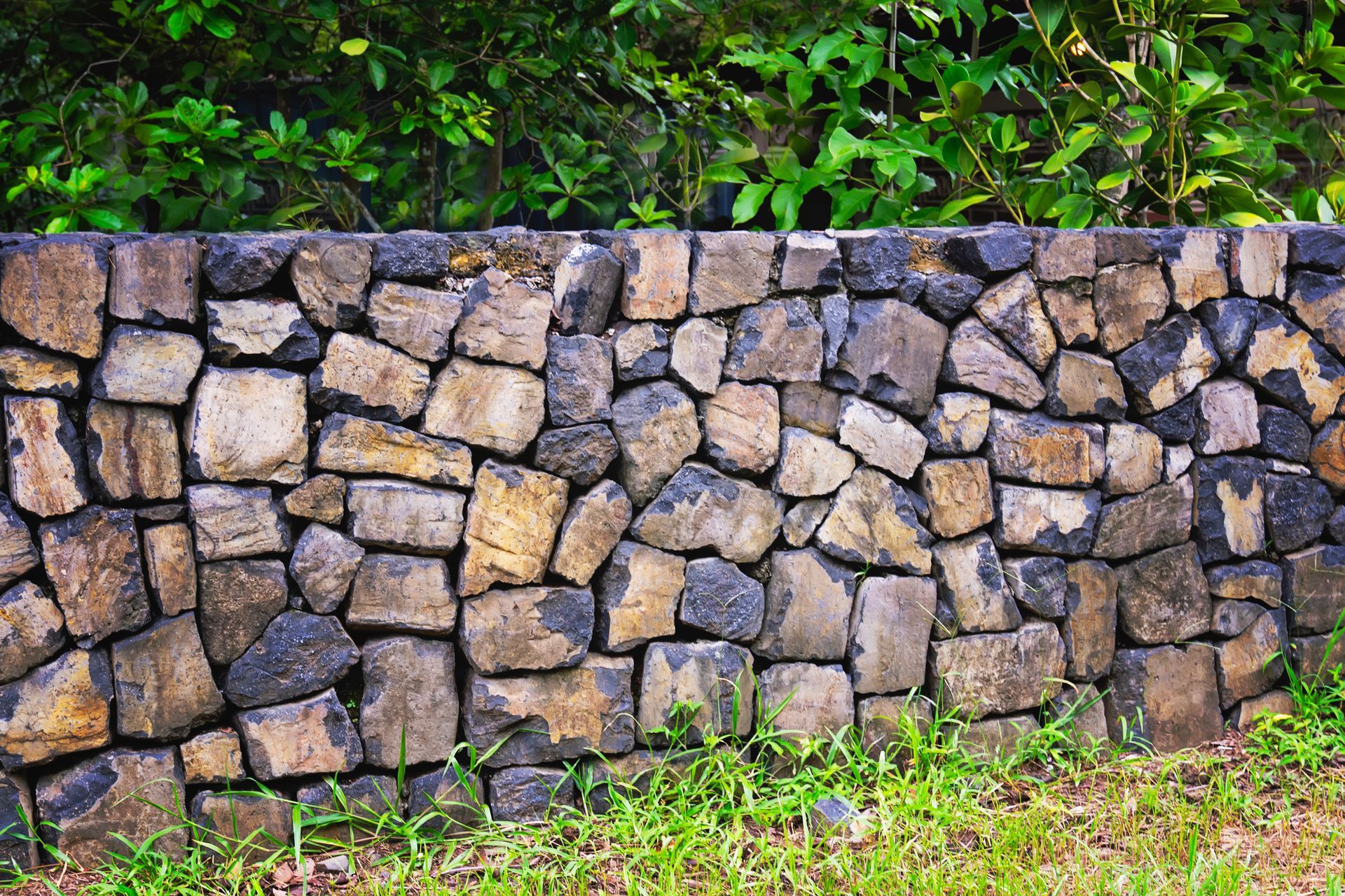 A stone wall is surrounded by grass and trees.