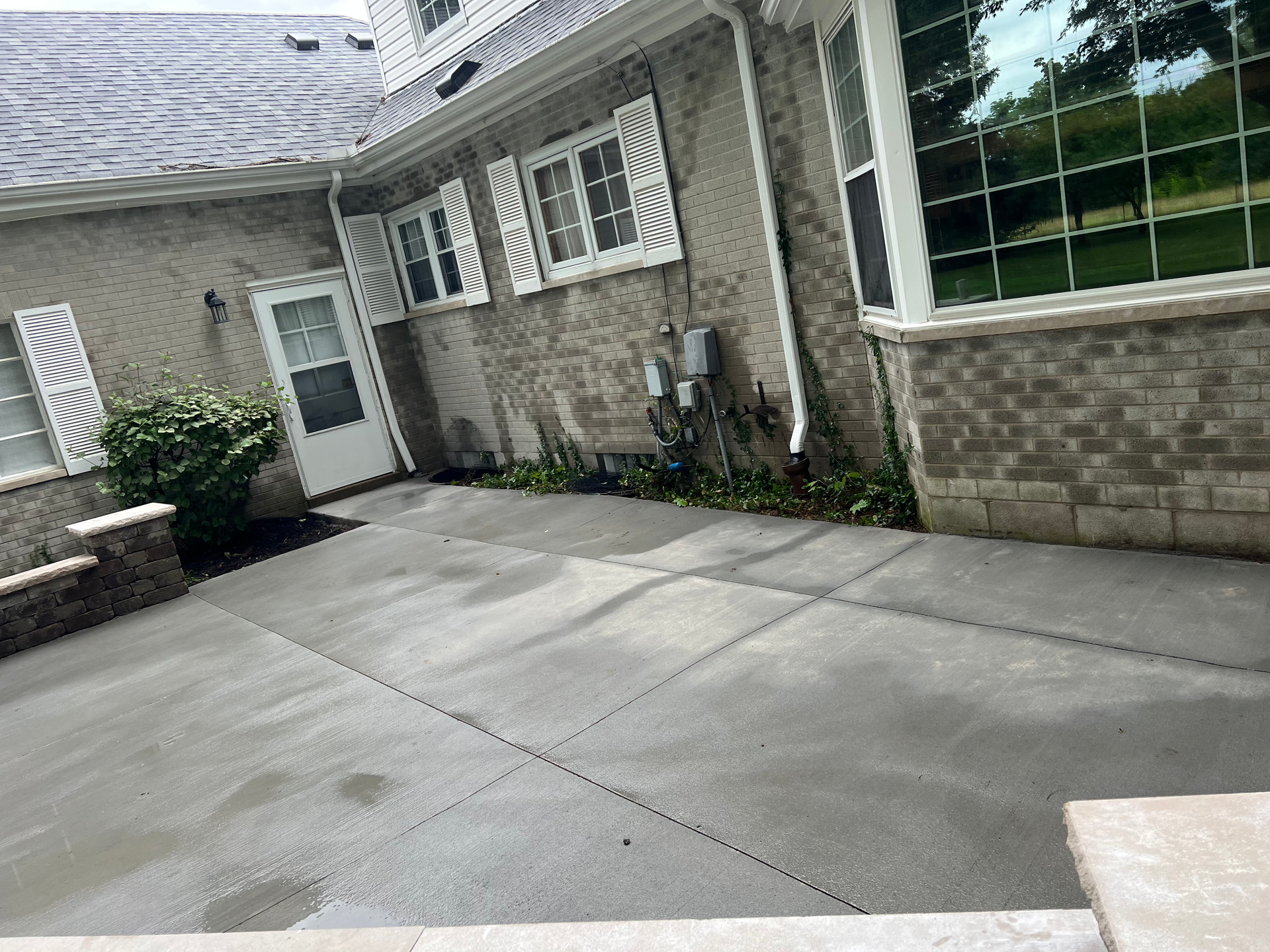 A brick house with a concrete driveway in front of it.