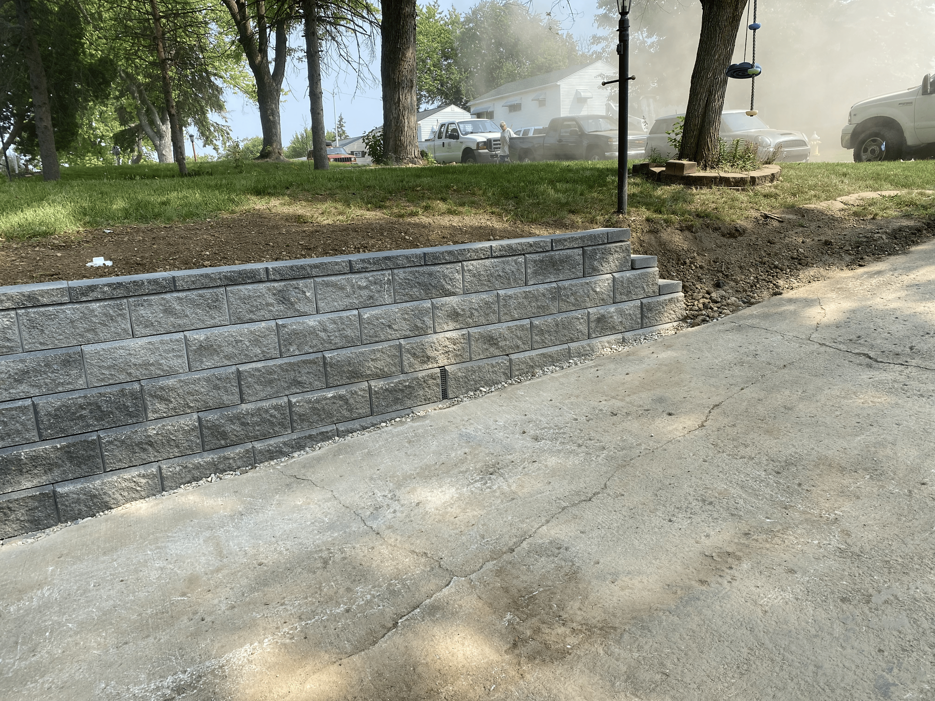 A brick wall is being built next to a driveway.