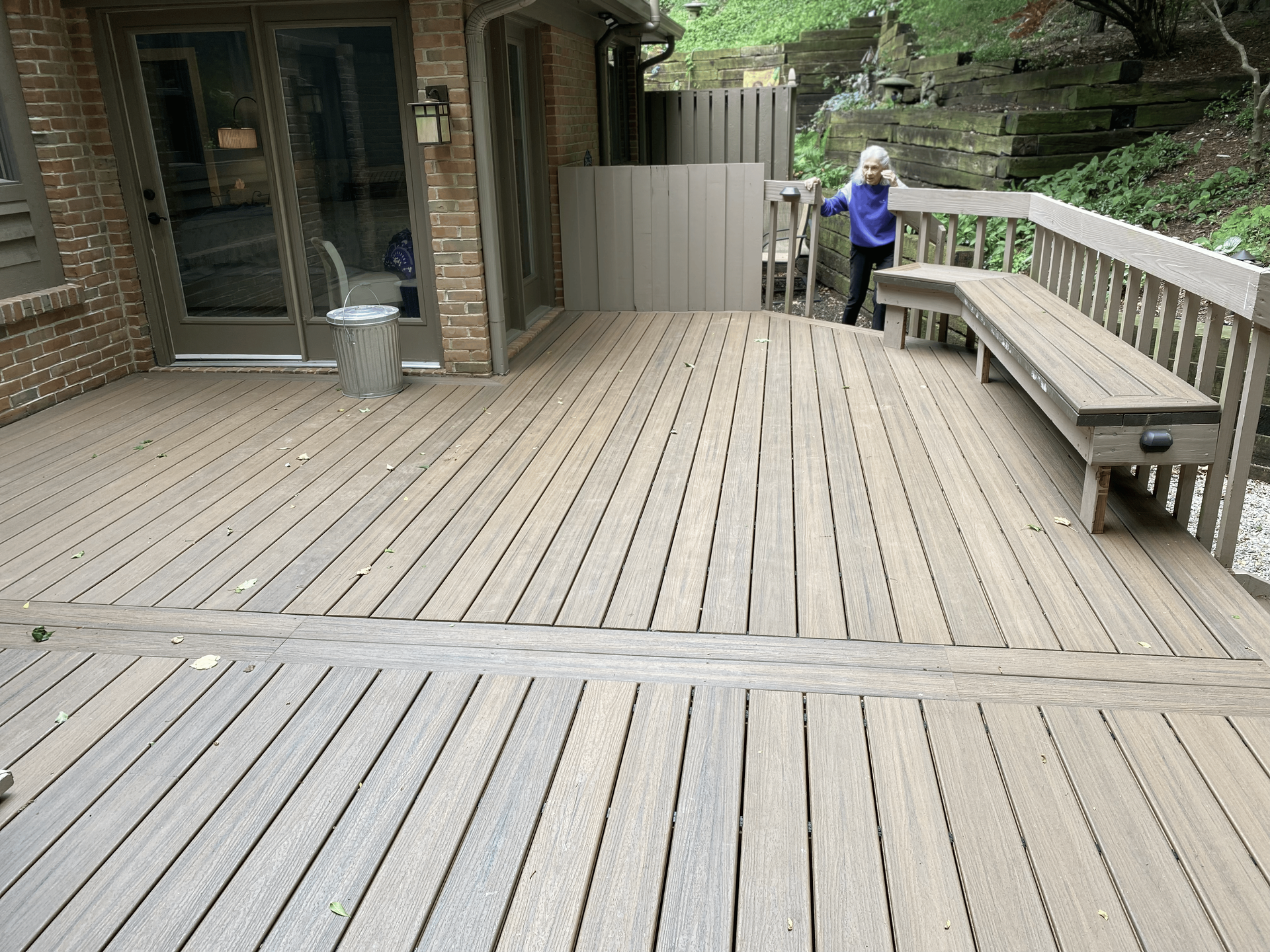 A child is standing on a wooden deck with a bench.