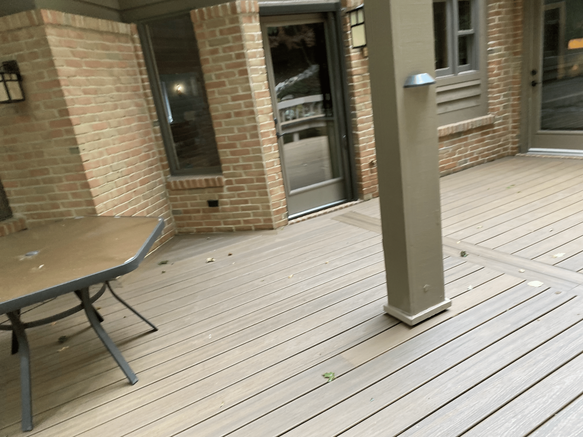 A deck with a table and chairs in front of a brick building