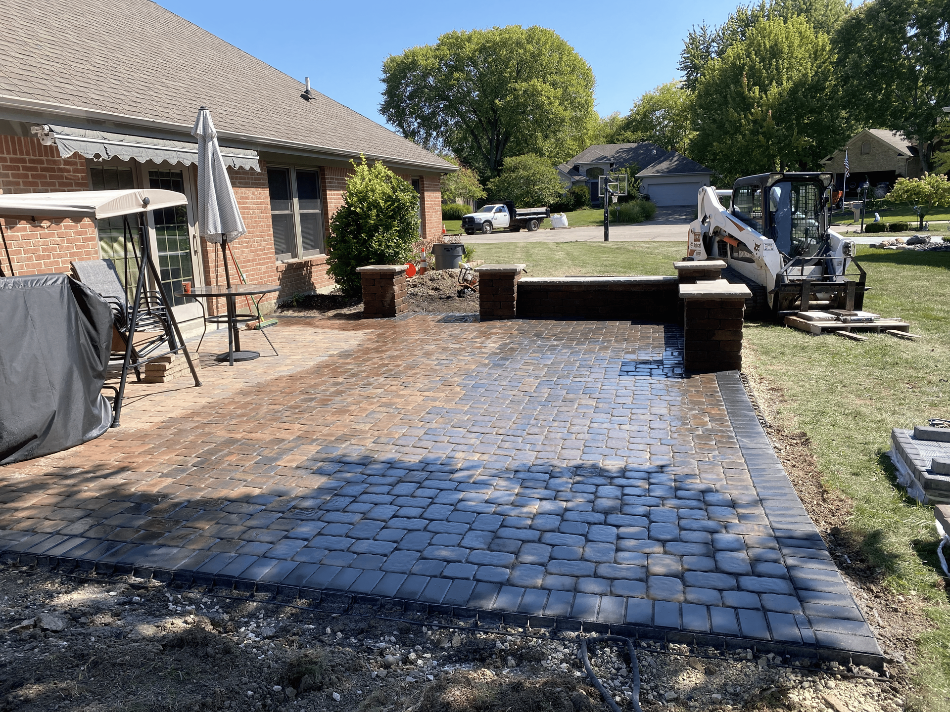 A brick patio is being built in front of a house.