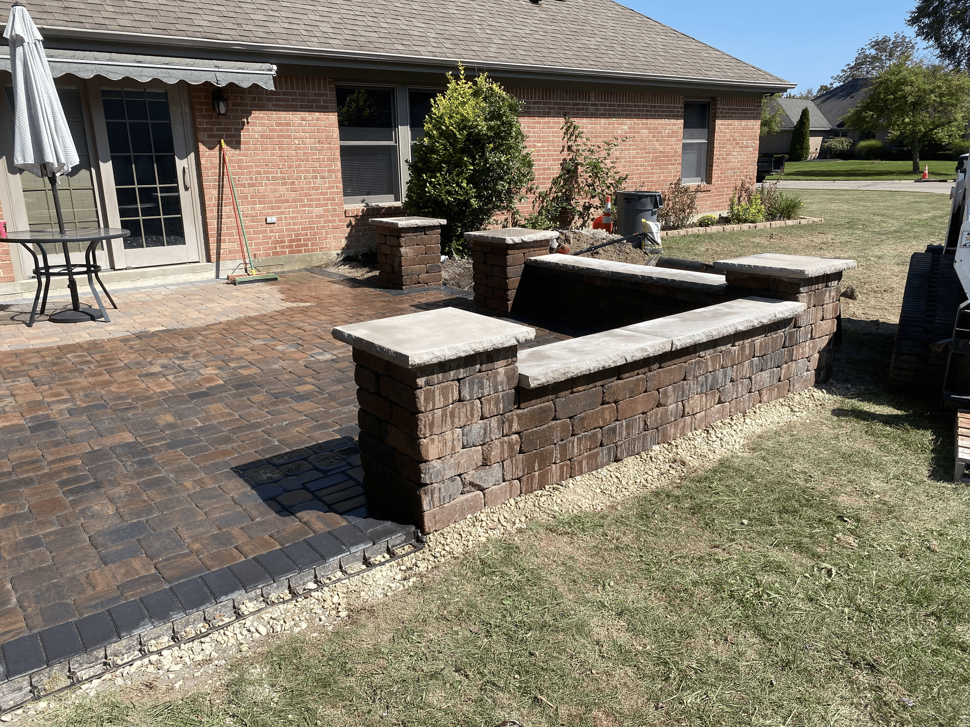 A brick wall is sitting in front of a brick house.