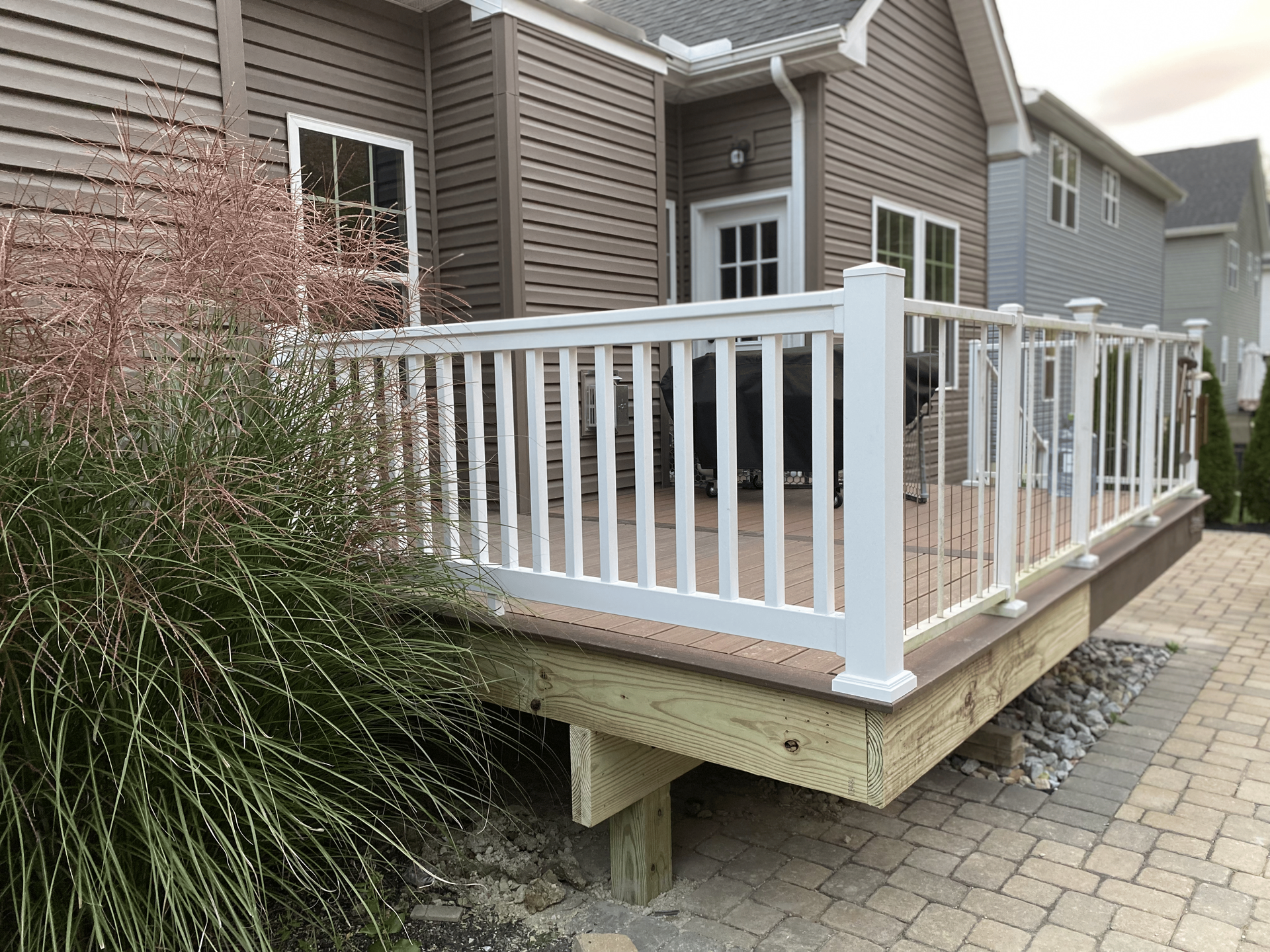 A deck with a white railing is in front of a house.